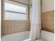 Compact bathroom featuring a shower-tub combination, tiled walls, and a frosted window at 1606 Burryport Dr, Orlando, FL 32837