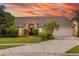 Inviting single-story home featuring a two-car garage, beautifully landscaped yard, and a striking pink exterior at sunset at 1606 Burryport Dr, Orlando, FL 32837