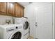 Functional laundry room equipped with a washer, dryer, and overhead wooden cabinets at 1606 Burryport Dr, Orlando, FL 32837