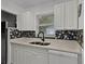 Bright kitchen featuring white cabinets, stone countertops, and a stylish mosaic tile backsplash at 1649 Weybridge St, Deltona, FL 32725