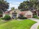 Charming single-story home with a well-manicured lawn and mature trees, a two-car garage, and a delightful blue front door at 165 Fig Tree Run, Longwood, FL 32750