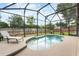 Backyard oasis with a screened-in pool, lounge chair, and lush green surroundings at 165 Fig Tree Run, Longwood, FL 32750