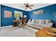 Modern home office featuring a comfortable sofa, a work desk, and a bright blue accent wall at 1916 Excalibur Dr, Orlando, FL 32822