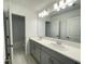 Bathroom featuring double sinks, gray vanity and ample lighting above a large mirror at 228 Aquamarine Ln, Kissimmee, FL 34758