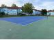 An outdoor tennis court with a new blue surface surrounded by trees and blue residential buildings at 2739 N Poinciana Blvd # 77, Kissimmee, FL 34746
