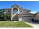 Two story home featuring an arched entryway, attached two-car garage, and front lawn at 402 Big Sioux Ct, Kissimmee, FL 34759