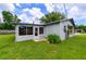 The backyard features lush grass, a white house, and an enclosed porch with several windows at 4469 Evers Pl, Orlando, FL 32811