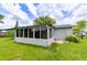 A well-maintained backyard with green grass and an enclosed patio with many windows at 4469 Evers Pl, Orlando, FL 32811