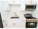 Modern kitchen featuring white cabinetry, gold hardware, stainless steel appliances, and a tile backsplash at 4469 Evers Pl, Orlando, FL 32811