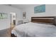 Bedroom with wood floor, artwork, and chair; furnished with a wooden bed, and side table; view into bathroom at 461 Diamond Dove Cv, Winter Springs, FL 32708