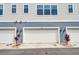 Garage of home featuring a white door with address number, sconce lighting, and minimalist landscaping at 461 Diamond Dove Cv, Winter Springs, FL 32708