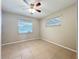 A simple bedroom with tile floors, ceiling fan, and natural light from two windows at 4757 Goldsboro Ct, Orlando, FL 32811