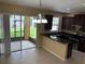 Kitchen featuring tile floors, dark cabinets, granite countertops, and access to a screened patio at 5377 Via Appia Way, Sanford, FL 32771
