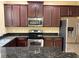 Kitchen with granite countertops, stainless steel appliances, and dark wood cabinets at 5377 Via Appia Way, Sanford, FL 32771