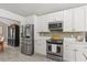 Functional kitchen area with stainless steel appliances, white cabinets, and a view into the dining area at 645 Macglenross Dr, Oviedo, FL 32765