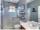 Well-lit bathroom featuring a glass-enclosed shower, updated vanity, and decorative shelving, providing a clean and modern space at 697 Broadoak Loop, Sanford, FL 32771