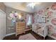 Charming Bedroom featuring floral wallpaper, a crib, and a wooden dresser at 697 Broadoak Loop, Sanford, FL 32771