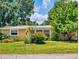 A cozy single-story home features a metal roof, lush landscaping, and a well-manicured lawn, creating a welcoming facade at 706 Lynn Ave, New Smyrna Beach, FL 32168