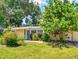 Charming home with a lush green lawn, mature landscaping, and a welcoming blue front door at 706 Lynn Ave, New Smyrna Beach, FL 32168