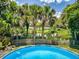 Backyard view of the pool with a fence separating it from the lake and lush tropical palm tree landscape at 706 Lynn Ave, New Smyrna Beach, FL 32168