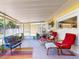 Relaxing screened porch with colorful seating, plants, and charming decor, ideal for outdoor enjoyment at 706 Lynn Ave, New Smyrna Beach, FL 32168