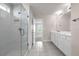 Bright bathroom featuring a glass shower, gray tile flooring, and a double sink vanity with white cabinets at 7367 Catania Loop, Clermont, FL 34714