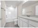 A full bathroom with a single sink vanity, quartz countertop, tiled floor, and tub with tiled walls at 7367 Catania Loop, Clermont, FL 34714