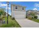 Two-story home featuring gray siding and a white two-car garage, complemented by landscaped yard at 7367 Catania Loop, Clermont, FL 34714