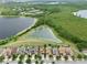 Aerial view of the neighborhood, pond, and conservation area featuring lush green trees and well-kept landscaping at 8752 Lookout Pointe Dr, Windermere, FL 34786