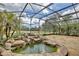 Large screened lanai with rock waterfall and peaceful views of the scenic backyard pond and trees at 8752 Lookout Pointe Dr, Windermere, FL 34786