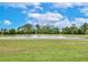 Scenic view of a pond surrounded by lush greenery under a bright, partly cloudy sky at 8752 Lookout Pointe Dr, Windermere, FL 34786