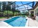 A stunning screened-in pool with blue tile accents and a serene view of lush landscaping at 100 Verde Way, Debary, FL 32713