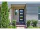 Close-up of a modern front door with glass panels, flanked by lush greenery and brick accents, offering a warm welcome at 10120 Sunnifa Aly, Orlando, FL 32832