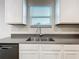 Close-up of the kitchen sink area with white cabinets, gray counters, and a window at 16436 Fernridge St, Clermont, FL 34714