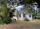 Inviting single-story home with a white exterior and charming curb appeal, surrounded by lush greenery at 200 W Doane Ave, Eustis, FL 32726