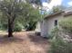 Exterior side view of the home surrounded by mature trees, landscaping, and an AC unit visible at 200 W Doane Ave, Eustis, FL 32726