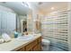 Bright bathroom features a vanity with sink, mirror and cabinet, plus a toilet and shower with blue and green striped curtain at 214 Paloma Dr, Davenport, FL 33837