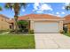 Welcoming home featuring a terra cotta roof, two-car garage, and lush green lawn at 214 Paloma Dr, Davenport, FL 33837