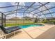 Relaxing pool and spa area within a screened enclosure, featuring lounge chairs for leisurely enjoyment at 214 Paloma Dr, Davenport, FL 33837