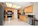 Kitchen has stainless steel appliances, white tile floor, light wood cabinets, and offers a functional cooking space at 2430 Westwood Dr, Longwood, FL 32779
