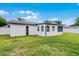 Exterior view of the home showcasing the screened-in porch and a lush, green backyard at 2932 Carriage Dr, South Daytona, FL 32119