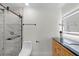 Bright bathroom showcases a tiled walk-in shower with glass door, toilet, black fixtures, and a wooden vanity with a lighted mirror at 2932 Carriage Dr, South Daytona, FL 32119