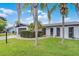 Charming single-story home showcasing lush landscaping and mature palm trees against a blue sky at 2932 Carriage Dr, South Daytona, FL 32119