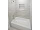 Bright bathroom with white tub, tiled walls, and recessed shelving for storage at 311 Osceola Ave, Lake Wales, FL 33853