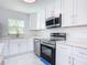 Modern kitchen with white cabinets, stainless steel appliances, and quartz countertops at 611 S Montgomery Ave, Deland, FL 32720