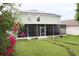 Spacious screened lanai in backyard with green lawn; solar panels on roof at 115 Willowbay Ridge St, Sanford, FL 32771