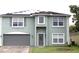 Two-story home featuring a gray front door, a two-car garage, solar panels and manicured green lawn at 115 Willowbay Ridge St, Sanford, FL 32771