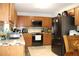 Well-lit kitchen featuring tile countertops, wood cabinets, and modern black stainless steel appliances at 115 Willowbay Ridge St, Sanford, FL 32771