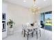 Dining area featuring modern lighting, a marble table, and an open view to the outdoor patio with a grill at 13829 Destin Beach Ln, Orlando, FL 32827