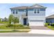 Two-story home featuring blue siding, a well-manicured lawn, and a two-car garage with a brick-paved driveway at 13829 Destin Beach Ln, Orlando, FL 32827